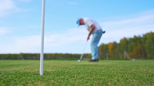 A Golfer Concentrating While Putting on the Green Under a Beautiful Clear Blue Sky