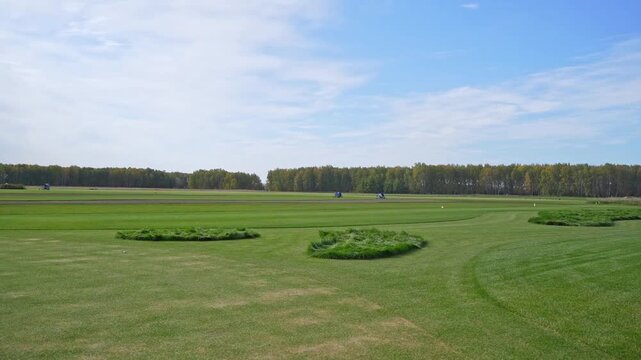 Focused man practicing golf swing on driving range with greenery in background. Outdoor recreational activities and sports training.