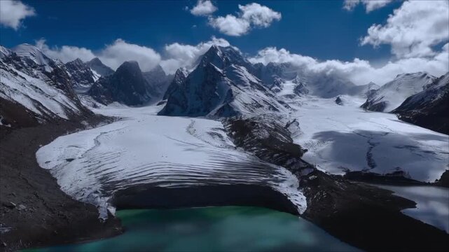 Aerial view of glacial lake and massive ice tongue surrounded by snow capped mountain peaks and turquoise alpine water