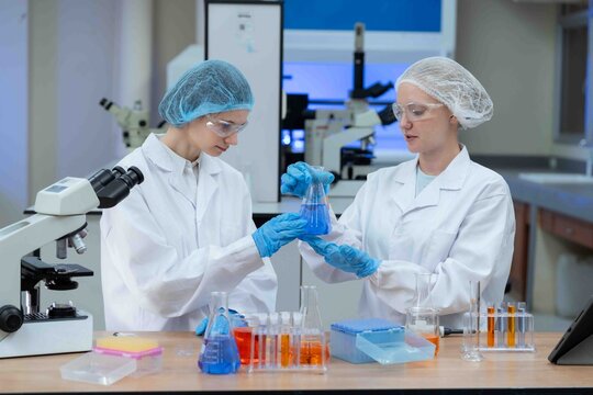 Two Asian female scientists talk Discuss concepts and use PC in evaluating research data in Medical research center laboratory medical science concept.