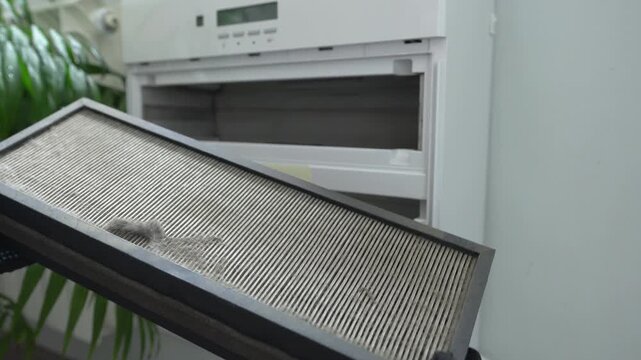 Dirty air filter. Gloved hands remove a dirty filter from the air purification system.