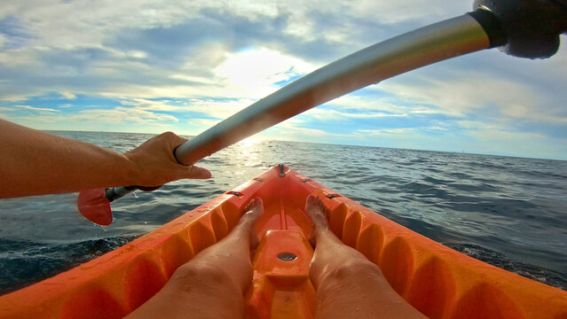 A young couple paddles through the shimmering sea, their hands gripping the oar as they navigate the waves. The horizon stretches out, inviting them deeper into this adventurous escape.