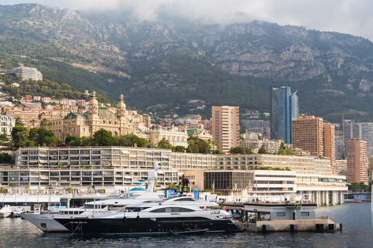 MONACO - JULY 17, 2026: Scenic view of Monte Carlo Casino, luxury yachts in Port Hercule, and high-rise buildings against steep mountains.