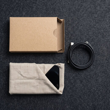 Linen wrapped device with coiled cable dark minimal Cyber Monday tech gift, flat lay with copy space on right