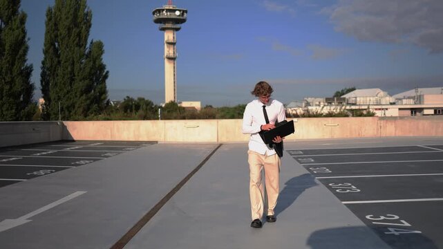 Young inexperienced employee works everywhere and even on the go checking his laptop while walking outdoors as he struggles to prove himself and manage a demanding new job daily