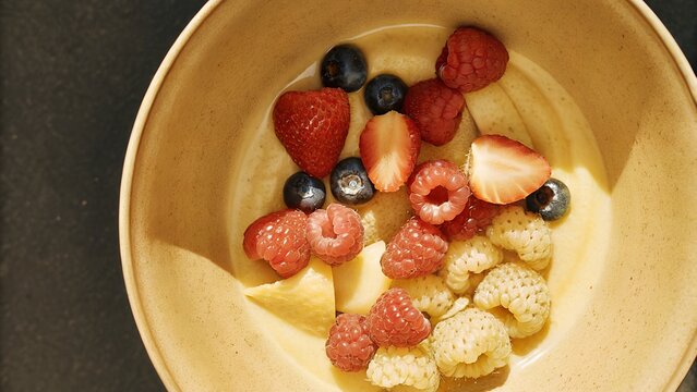 A bowl of fresh colorful berries including strawberries blueberries and raspberries top view