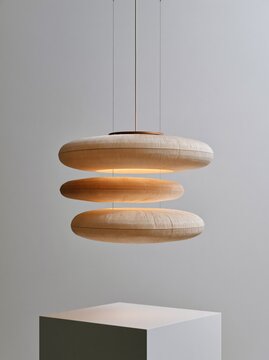 Modern layered pendant light fixture with textured circular shades in a minimalist interior setting