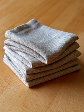 Stack of folded linen napkins on a wooden table with natural light and copy space