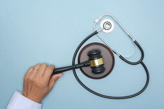 Serious doctor holds gavel near stethoscope seeking justice and ethical law enforcement against medicine malpractice in court