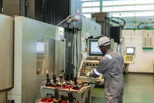 Black Engineer Operating CNC Machine in Factory Checking Industrial Manufacturing Process Control