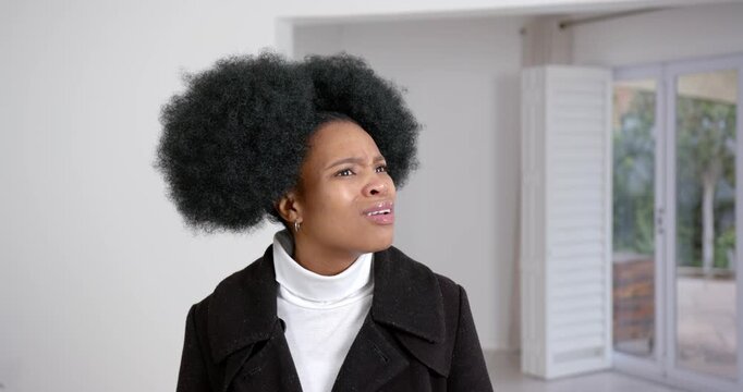 High speed photography for dynamic scenes, woman in black coat looking puzzled, standing indoors wit