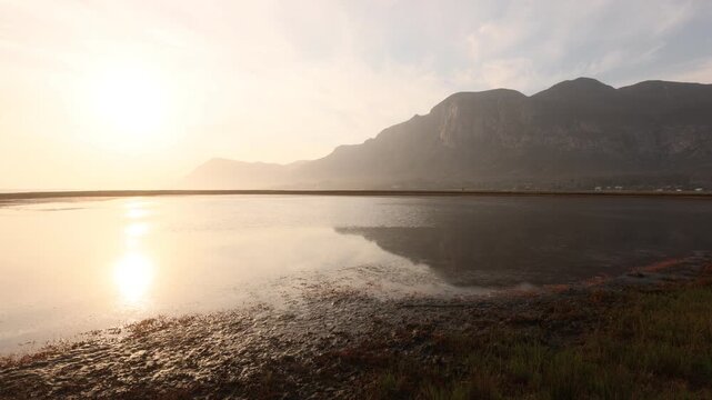 pale sunset over lagoon and reflection of klein mountains, stanford, south africa