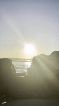 Ocean waves crashing on rocky beach with golden sunset reflection in Aceh Indonesia