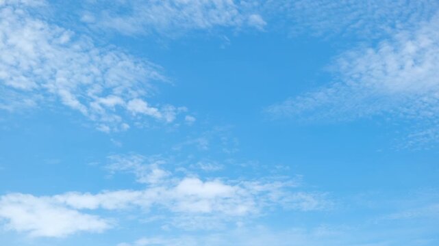 Blue sky cloud timelapse video featuring soft cumulus and thin cirrus clouds drifting in gentle winds under sunlight, illustrating calm weather, atmospheric motion, and changing sky conditions. 4k.
