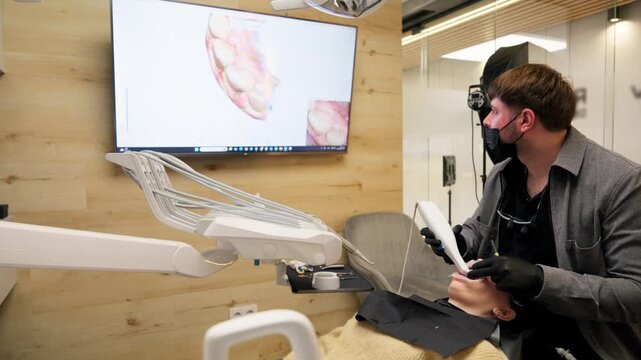 Professional orthodontist in a modern clinic scanning a patient's teeth with an intraoral scanner, creating a detailed 3d digital model of the jaw displayed in real-time on a monitor