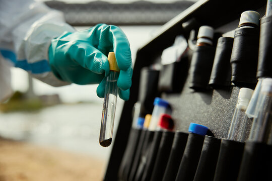 Environmental researcher hand holding test tube with water sample for chemical contamination analysis. Close up shot useful for ecological research and pollution control campaigns