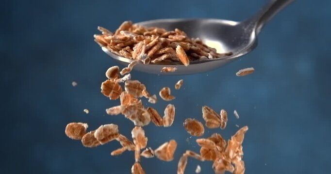 Oat flakes falling from a spoon in slow motion on blue background