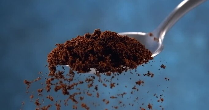 Ground coffee falling from a spoon in slow motion on blue background