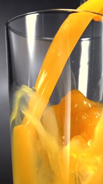 Fruit juice pouring into glass in slow motion on black background