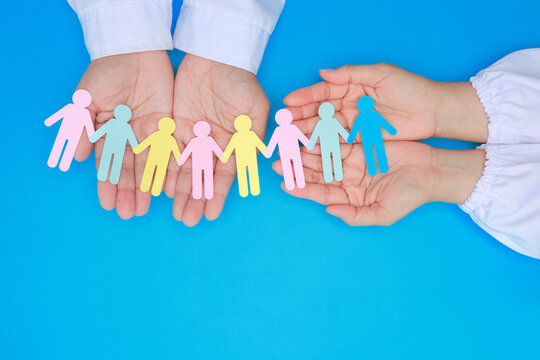 Doctor hand holding paper person chain showing multigenerational family care and support with joyful hope for unity on blue background