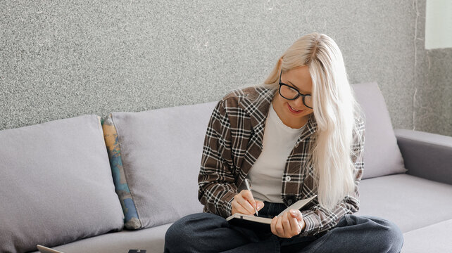Remote work and copywriting concept. Smiling freelance woman writing in notebook with large left side copy space.