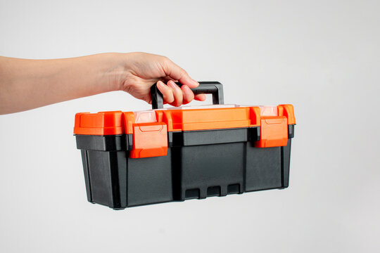 Toolbox; black toolbox held in hand; toolbox against a white background.