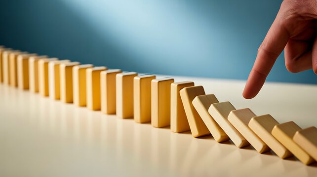 Domino tiles falling in sequence representing cause, effect, change, risk and chain reaction