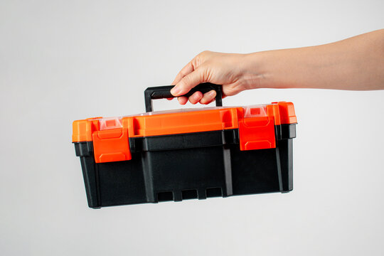 Toolbox; black toolbox held in hand; toolbox against a white background.