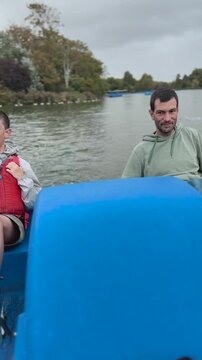 Father and son enjoying pedal boat ride on park lake
