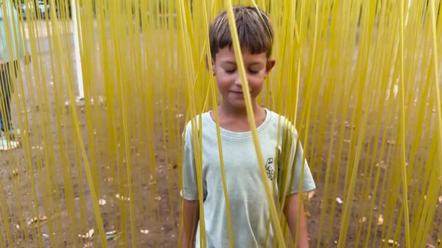 Boy playing among hanging yellow ribbons in outdoor park