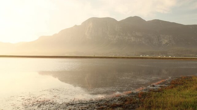 pale sunset over lagoon and reflection of klein mountains, stanford, south africa