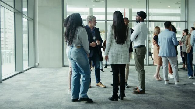 Diverse business professionals engaging in conversation and networking in a spacious conference venue. Colleagues gather, discussing ideas and building connections during an event.
