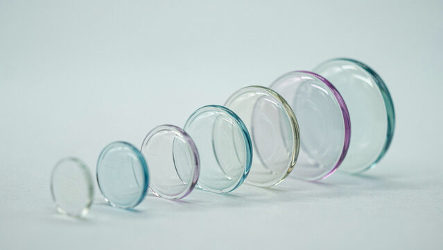 Progressive arrangement of circular glass lenses on neutral background as isolated element