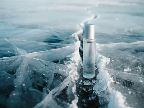 A metal ice auger drill bit standing upright in a hole cut through thick frozen lake ice