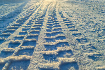 Obraz premium Tire tracks on winter snow road background for life journey concept and future dreams inspiration. Clear car tire track marks heading towards the bright horizon on a snowy path