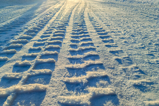 Tire tracks on winter snow road background for life journey concept and future dreams inspiration. Clear car tire track marks heading towards the bright horizon on a snowy path