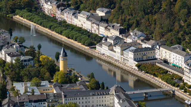 Aerial view of the Lahn river flowing through Bad Ems, featuring the Kurhaus, a yellow tower, and tree-lined promenades in Bad Ems, Rhineland-Palatinate, Germany.