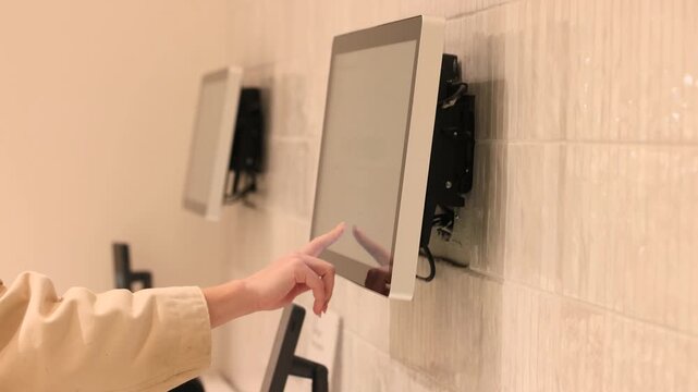 Hand taps wall mounted display panel with exposed wiring behind