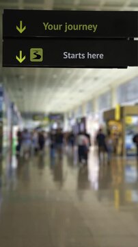 Inspiring airport sign with the message Your journey starts here with a blurred background of travelers walking through the terminal, creating a concept of new beginnings and adventure
