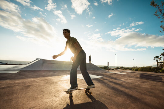 Young people having fun at skateboard park outdoor at sunset - Extreme sport concept - Main focus on guy body - UGC wide lens content