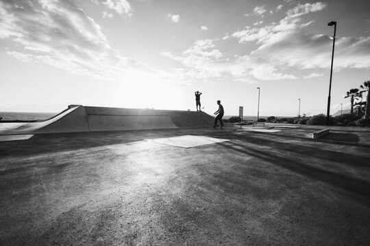 Young people having fun at skateboard park outdoor - Summer lifestyle and extreme sport concept - Soft focus on right guy body - Black and white film camera editing