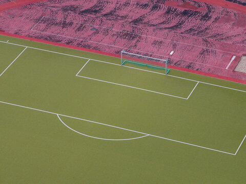 Aerial view of High-Deck-Siedlung sports field with green turf, white boundary lines, and a goal post, adjacent to a red running track in Berlin, Berlin, Germany.
