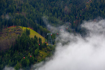 Mist curls through forested mountains. Cable car system rises above green hills. Trees stand tall, misty and quiet. Peaceful, untouched natural landscape. Ideal for travel, nature, or adventure themes © Alexandr