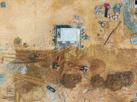 Aerial view of a construction area featuring excavators working on a site with piles of earth, building foundations, and scattered materials in Bukit Tambun, Penang, Malaysia.