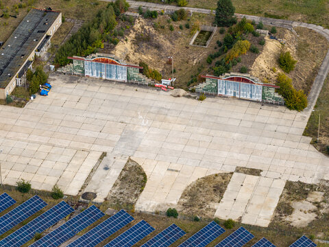 Aerial view of the solar field at the former military airfield in Preschen, featuring historic hangars and concrete taxiways near rows of solar panels in Neisse-Malxetal, Brandenburg, Germany.