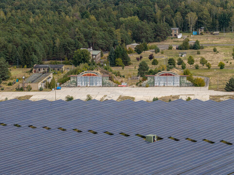 Aerial view of the solar field at the former military airfield in Preschen, featuring historic hangars and remnants of the runway and taxiway in Neisse-Malxetal, Brandenburg, Germany.