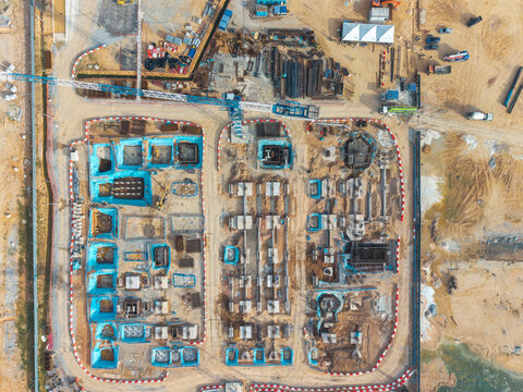 Aerial view of a construction area with foundation work, concrete footings, blue waterproof membranes, and a tower crane, Bukit Tambun, Penang, Malaysia.