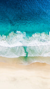 Aerial view of Modangan Beach with turquoise waves crashing on the sandy shore in Donomulyo, East Java, Indonesia.