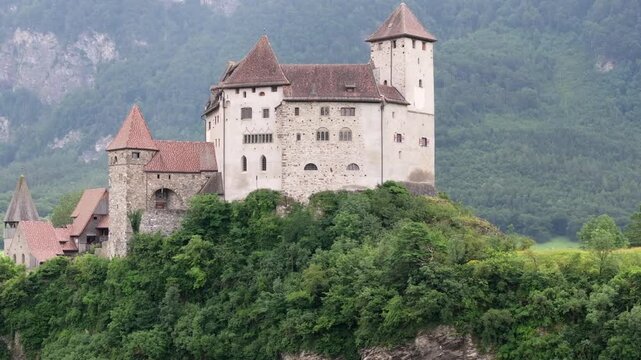 Aerial view of Gutenberg Castle perched on a rocky hill surrounded by lush green forests in Liechtenstein.