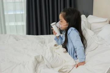 sick preschool child girl using respiratory nebulizer mask in bed © geargodz